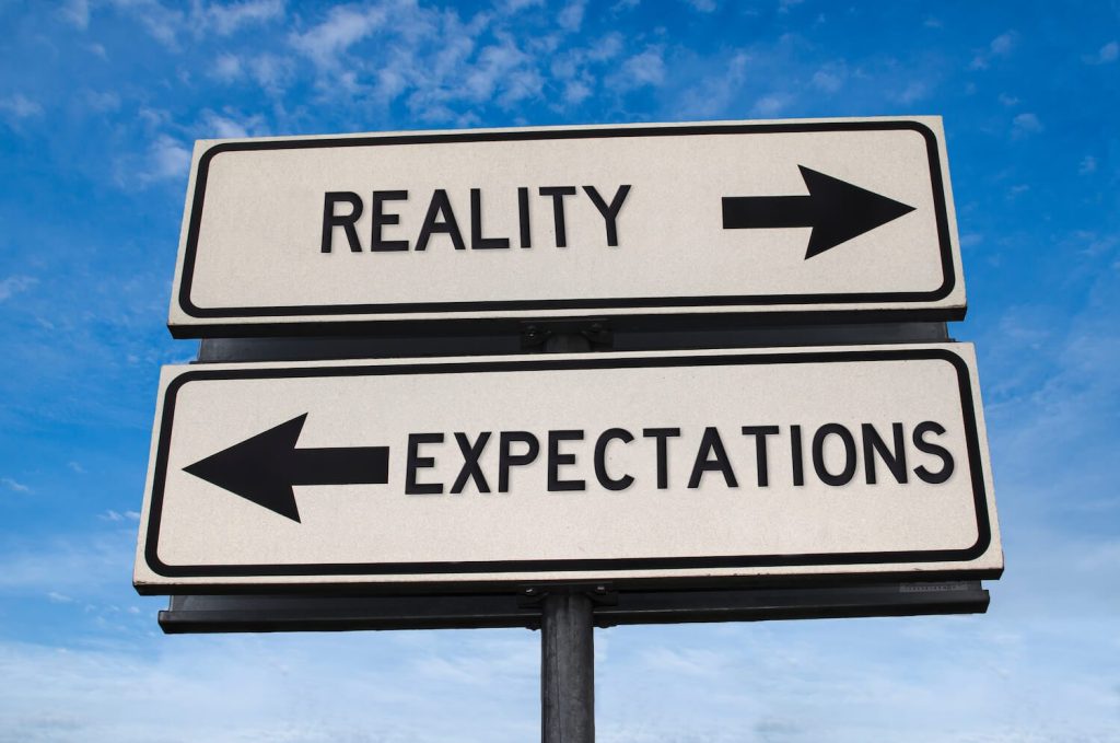 street sign indicating that expectations and reality go in opposite directions